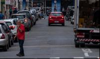 homem atravessa rua e caminhão está parado junto ao meio-fio