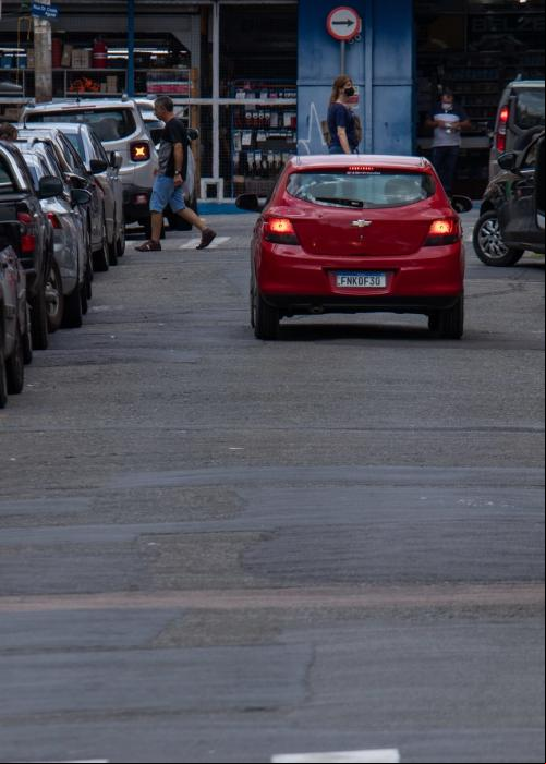 homem atravessa rua e caminhão está parado junto ao meio-fio